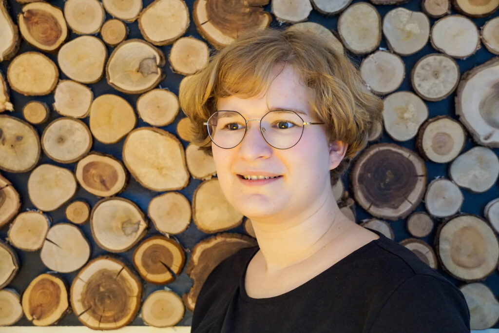 Portraitfoto von Hebamme Hanni vor rustikaler Holzwand